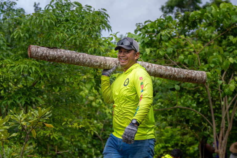 John Reynold holding a tree trunk