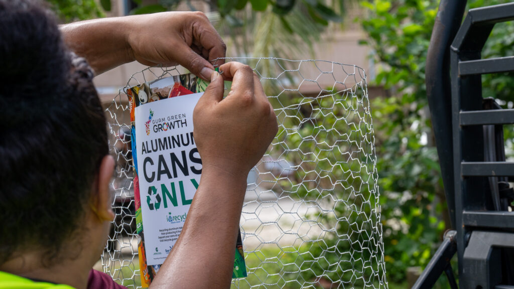 A G3CC member affixes a "Cans Only" sign to one of the can bins distributed throughout the parade route.