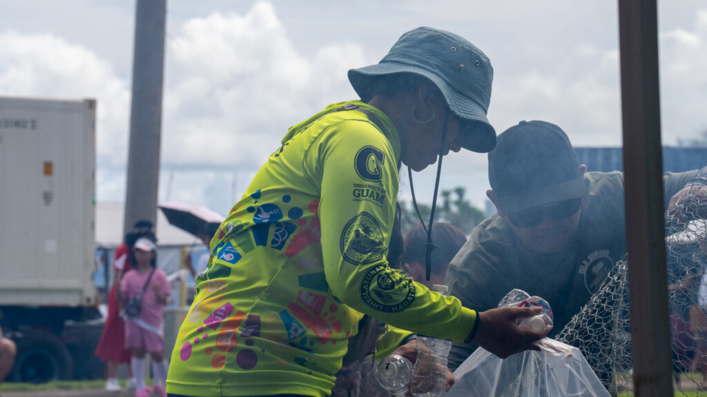 Marrae Cruz helps an celebrant at the 81st Liberation Day Parade sort a can bin.