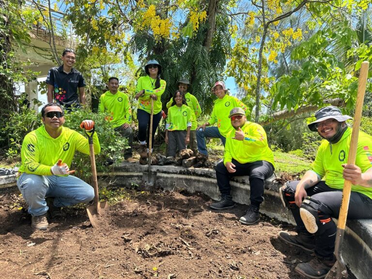 G3CC posing with shovels around a garden bed under a tree.