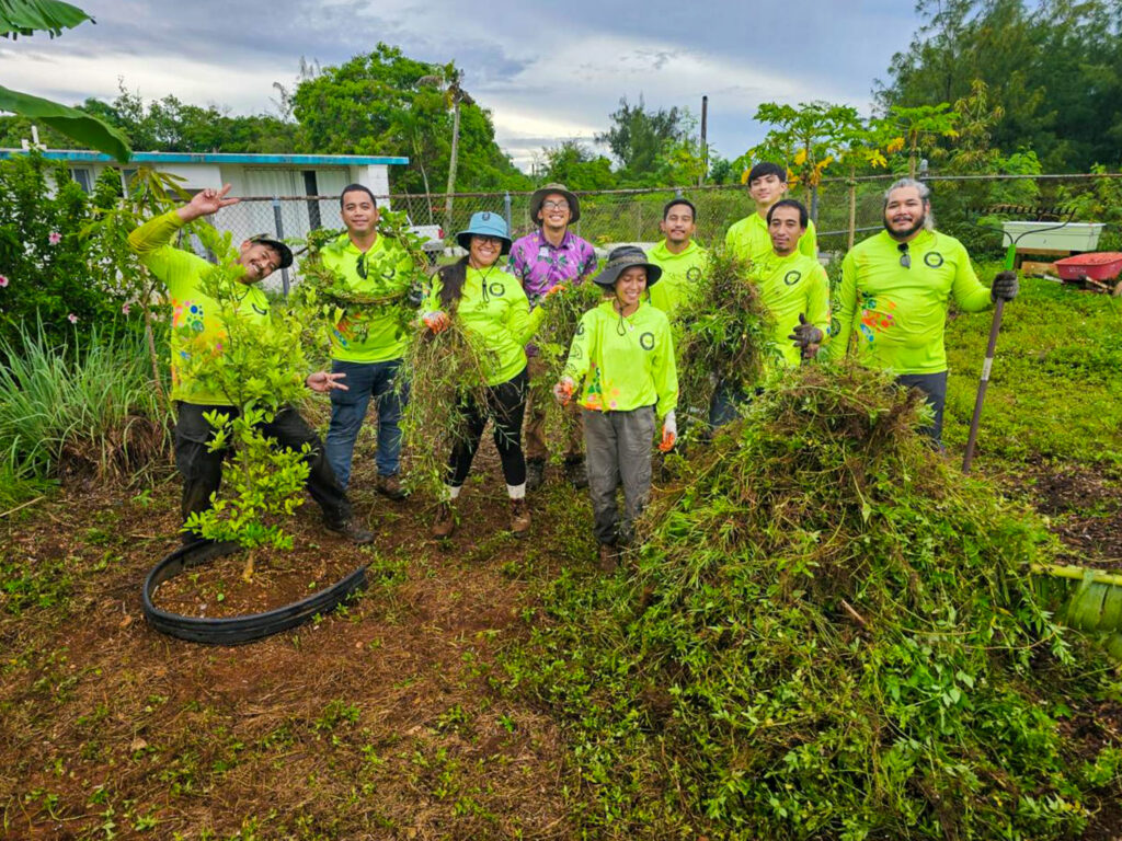 Members of the G3CC's fifth cohort showcase a large amount of brush removed from the Island Girl Power community garden