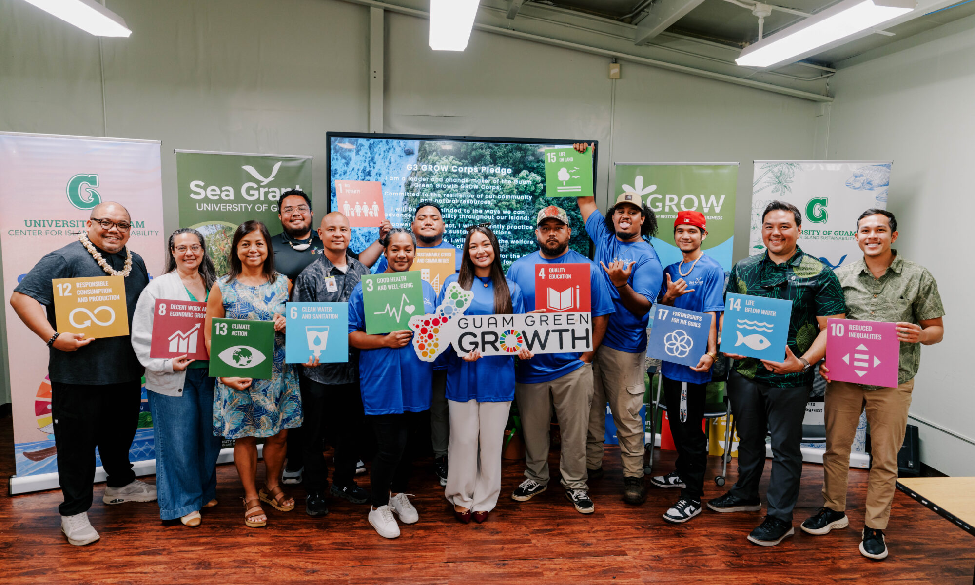The second G3 GROW Corps cohort and UOG CIS & Sea Grant leadership pose holding colourful Sustainable Development Goal signs and a Guam Green Growth plaque.